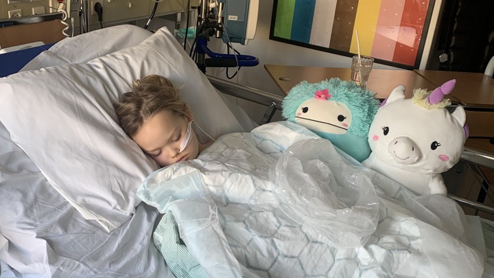 Alice ligger i en sjukhussäng och sover, med sond.