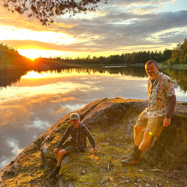 Pappa och son på en klippa i solnedgången
