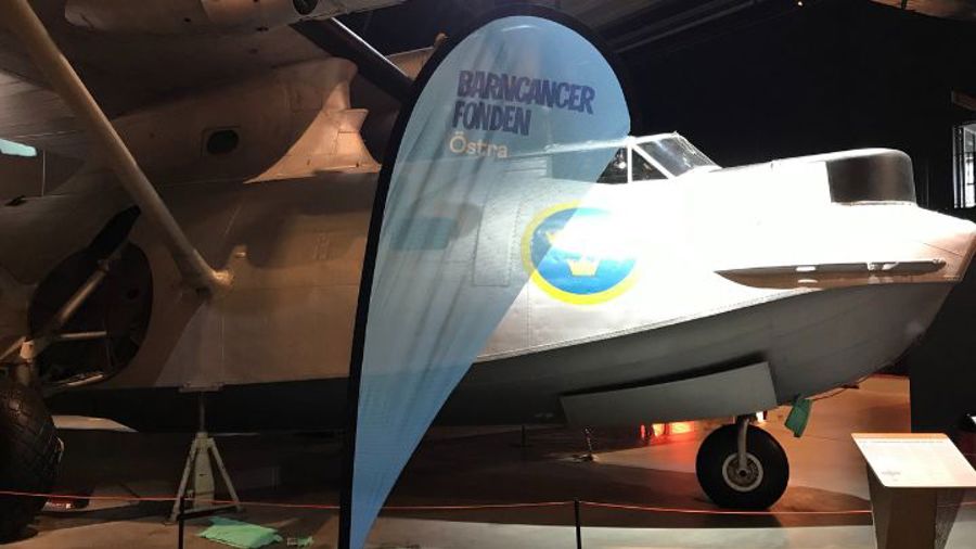 Flagga med BCF Östra logga framför gammalt flygplan