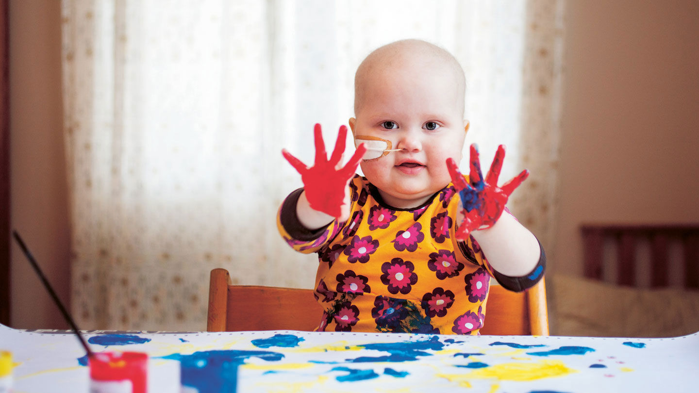 Hillevi fingermålar och visar upp båda sina händer, täckta med färg.