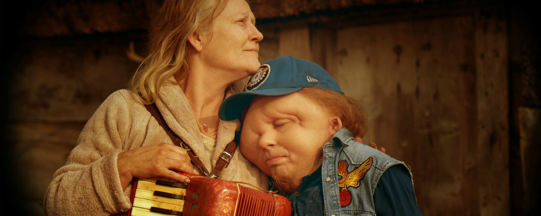 Stillbild från filmen Jätten. Christian Andréns karaktär lutar huvudet mot en annan karaktär.