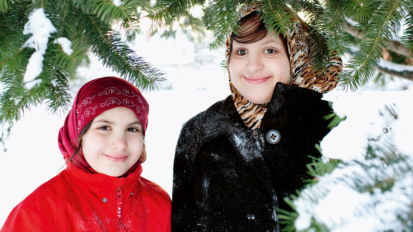 Shiema ler utomhus i snön tillsammans med sin lillasyster Israa.