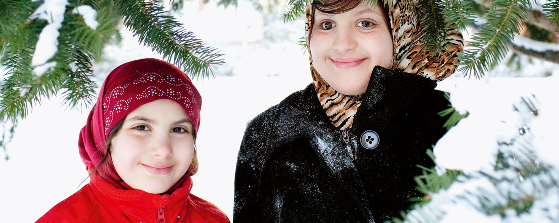 Shiema ler utomhus i snön tillsammans med sin lillasyster Israa.